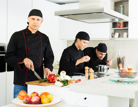 Portrait of the woman proffesional who is posing with devices in the kitchen