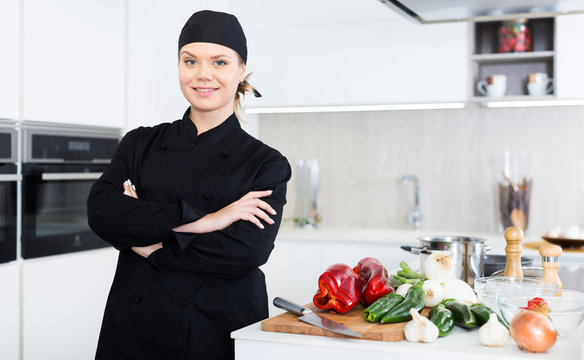 Portrait of the woman proffesional who is posing with devices in the kitchen