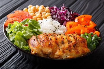 Healthy Buddha bowl with raw vegetables, grilled chicken, chickpeas, rice and greens close-up. horizontal