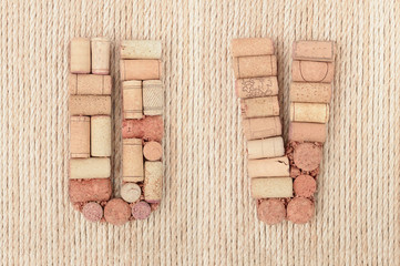 Alphabet letter U and V made of wine corks on jute rope background