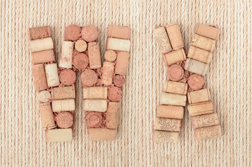 Alphabet letter W and X made of wine corks on jute rope background