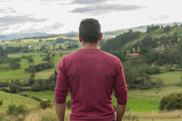 Man on the top of a mountain with his backs looking on horizon.