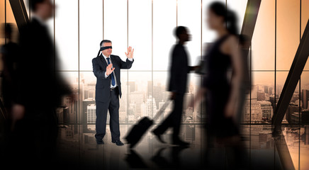 Mature businessman in a blindfold against busy room with large window looking on city