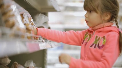 Little girl choosing foodstuff at grocery store