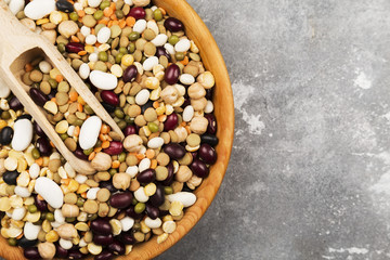 Assortment of beans (red lentil, green lentil, chickpea, peas, red beans, white beans, mix beans, mung bean) on gray background. Top view, copy space. Food background