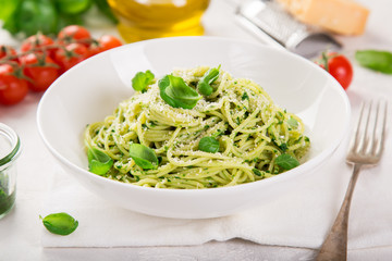 spaghetti pasta with basil pesto sauce and parmesan cheese on white bowl