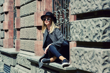 Portrait of a young woman in a felt hat in the city . The woman on the street wearing sunglasses