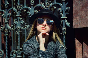 Portrait of a young woman in a felt hat in the city . The woman on the street wearing sunglasses