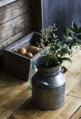 Rustic bouquet of herbs in aluminum cans, chicken eggs in box on the table