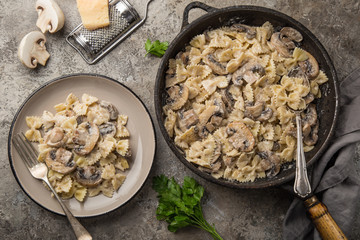 farfalle pasta with champignon mushrooms and garlic creamy sauce on pan