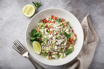 couscous and vegetables salad with feta cheese in white bowl