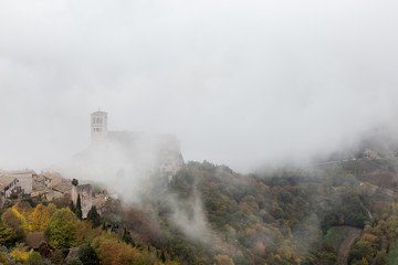 Fototapeta premium View of St. Francis papal church in Assisi (Umbria, Italy) in the middle of lifting morning fog