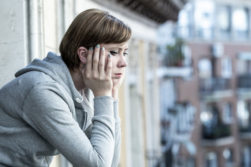 young attractive unhappy depressed lonely woman looking sad on the balcony at home - obrazy, fototapety, plakaty