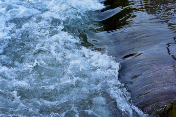 A close up photograph of a small waterfall made from stone wall, Small waterfall. The height...