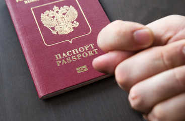 Men's Hand shows the fico on red passport backgound. Symbol of sanctions. Negative concept. Closeup