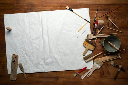 painting still life with paper, brushes and other tools on a wooden background