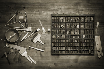 print still life with lettering, brushes and other tools on a wooden background