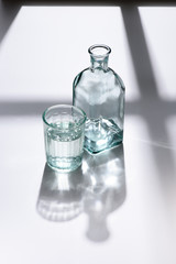 close up view of glass and bottle with water on white surface