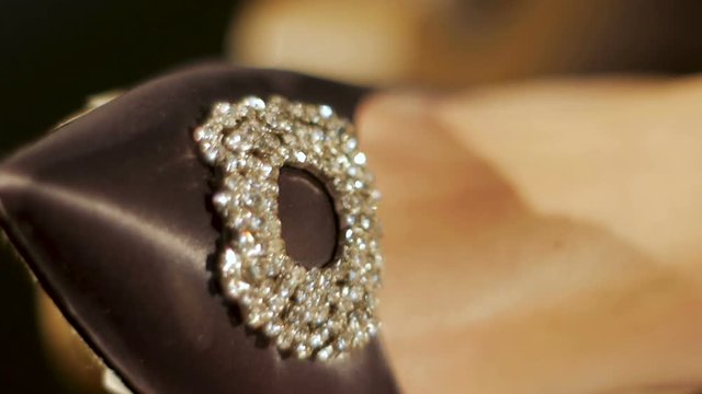 women's shoes clad feet with glittering stones at light