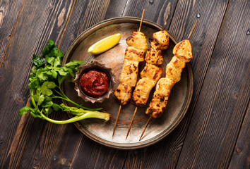 Shish kebab fillet of turkey on bamboo skewers on a metal plate, on a wooden table, top view