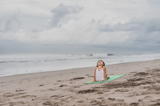 happy little child practicing yoga in Upward-Facing Dog (Urdhva Mukha Svanasana) pose on seashore - Powered by Adobe