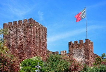 View of the Medieval castle with a Portuguese flag atop, Silves, Portugal.