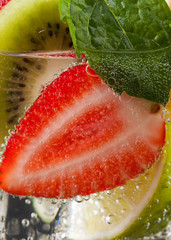 Panele Szklane  Owoce i jagody z listkami mięty w szklance wody gazowanej.
