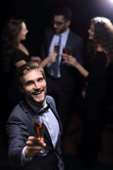 stylish young man standing with a glass of champagne.