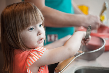 Little girl helps dad in a beautiful kitchen to cook food and wash dishes
