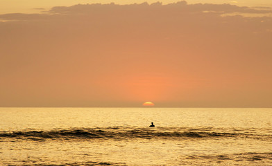 Fototapeta premium Surfer in the water enjoying the sun setting into the ocean