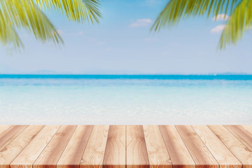 Empty wood table top and blurred Palm tree summer beach with blue sea and sky background. - can used for display or montage your products.