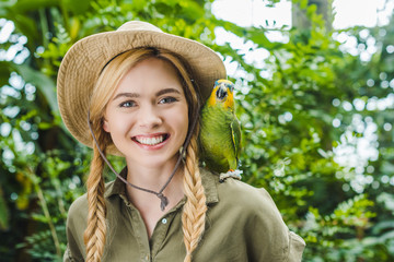 happy young woman in safari suit with parrot on shoulder in jungle © LIGHTFIELD STUDIOS