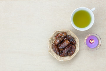 Table top view aerial image of decoration Ramadan Kareem holiday background.Flat lay date in wood basket with aromatherapy candle & green tea.Halal meal set for fasting is obligatory for Muslim.