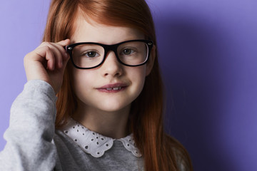 Fototapeta premium Redheaded girl adjusting glasses, portrait