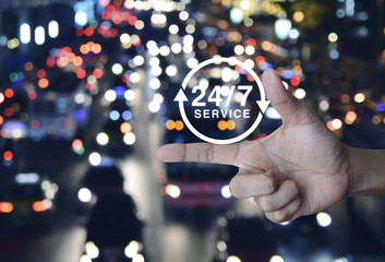 24 hours service icon on finger over blurred colourful night light city with cars, Full time service concept
