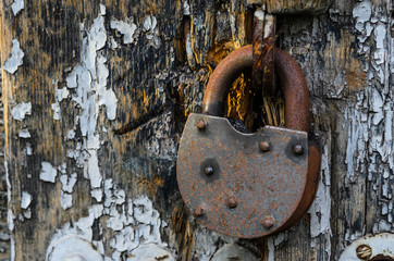 A rusty lock on the old vintage rural wooden gate.