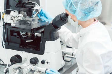 Woman doctor working in medical lab with manipulator and microscope