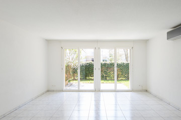 Large windows overlooking the garden in a completely empty room