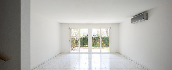 Large windows overlooking the garden in a completely empty room