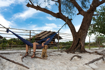 Woman sleeping on the hammock with dog accompany at the paradise beach of Koh Rong samloem island, Cambodia. 