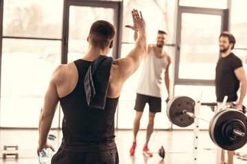 handsome sportsmen waving hands in gym