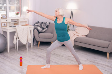 Obraz premium Healthy habit. Upbeat elderly woman stretching her arms and doing dynamic exercises during morning calisthenics