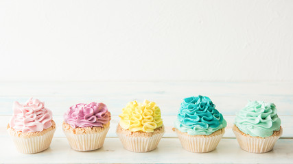 Five colorful cupcakes on a light background. Copy space