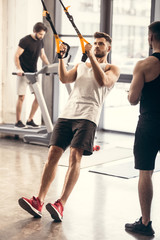 full length view of sporty young man training with resistance bands in gym
