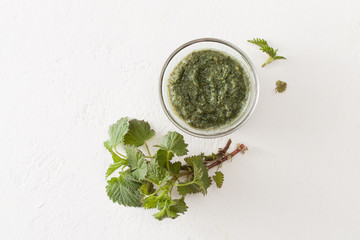 Fototapeta na wymiar Chopped nettle in a Cup and a sprig of fresh nettles on white