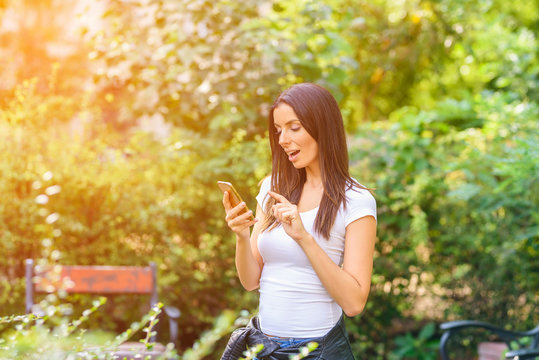 A cheerful woman in a Park using her Smartphone