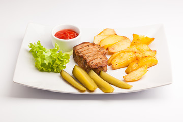 beautiful photo close-up menu of steak, potatoes,  salad on a plate on a white background