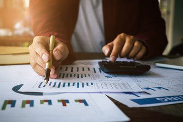 Close up Businessman using calculator and laptop for do math finance on wooden desk in office and business working background, tax, accounting, statistics and analytic research concept