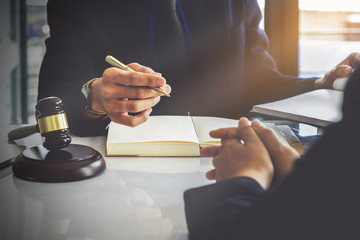 Business woman and lawyers discussing contract papers with brass scale on wooden desk in office....