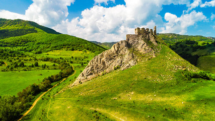Aerial view of Coltesti Fortress in Transylvania, Romania on a sunny spring day with green hills around and beautiful blue sky with clouds